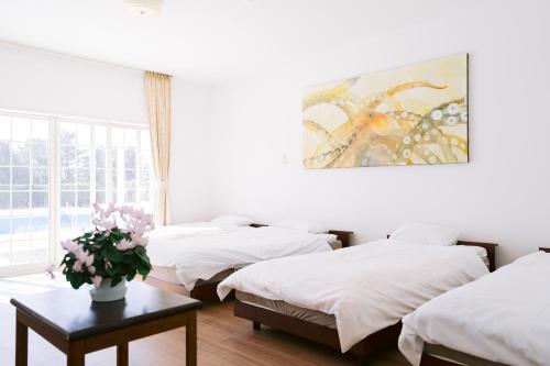 três camas num quarto com um vaso de flores sobre uma mesa em Hotel Kailani em Oshima