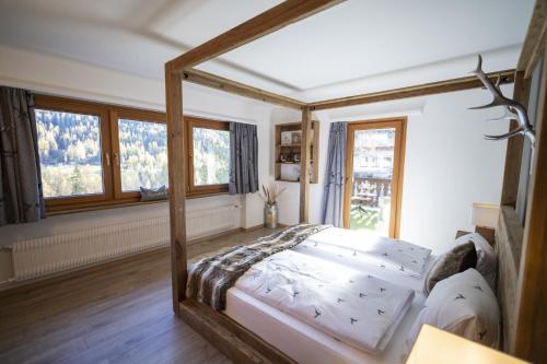 ein Schlafzimmer mit einem Himmelbett in einem Zimmer mit Fenstern in der Unterkunft Meis Chalet in Scuol