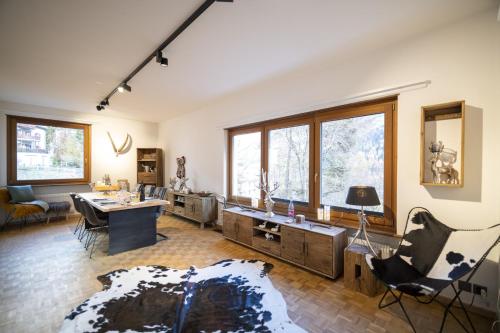 ein Wohnzimmer mit einem Schreibtisch, Stühlen und Fenstern in der Unterkunft Meis Chalet in Scuol