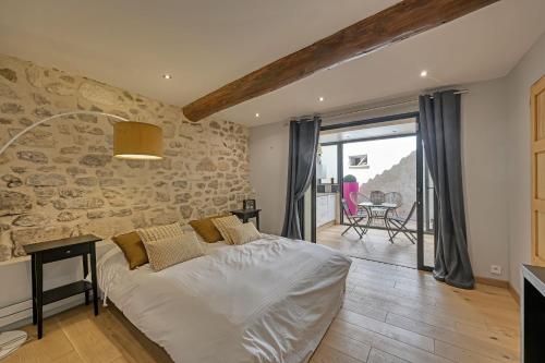 une chambre avec un lit et un mur en pierre dans l'établissement Maison Arti - Parking - Vue Palais des Papes - Rooftop, à Avignon
