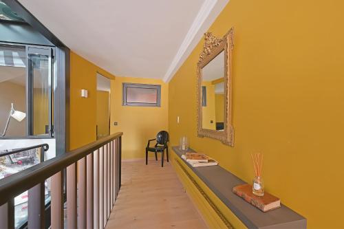 un couloir jaune avec un miroir et une chaise dans l'établissement Maison Arti - Parking - Vue Palais des Papes - Rooftop, à Avignon