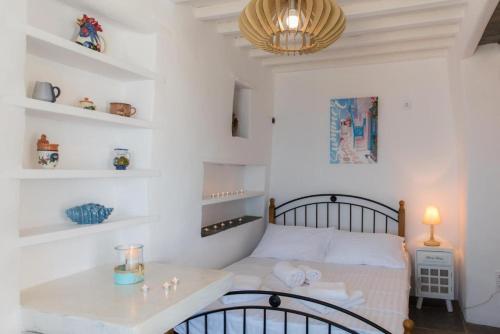 1 dormitorio con cama, mesa y estanterías en blue paradise villa, en Sifnos