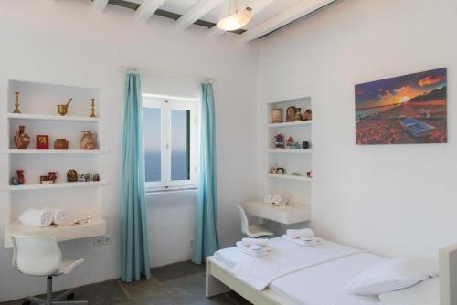 1 dormitorio con cama, escritorio y ventana en blue paradise villa, en Sifnos