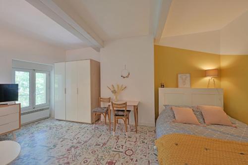 une chambre avec un lit, un bureau et une table dans l'établissement Le Balcon de l'horloge - AVIGNON - Centre ville, à Avignon