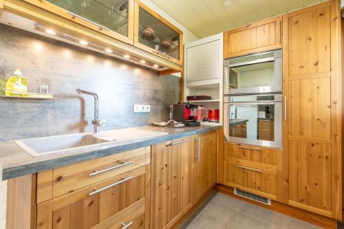 une cuisine avec des armoires en bois et un évier dans l'établissement Bel Appartement 8 couchages tout équipé- Maurice Thorez, à Clermont-Ferrand