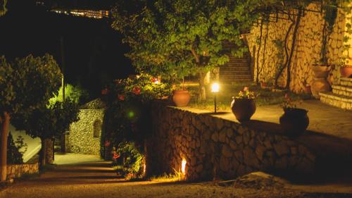 a stone wall with two potted plants on a street at night at Althea Studios Lefkada in Agios Nikitas