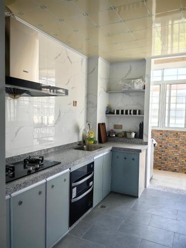 a kitchen with white walls and gray counter tops at Cozy home of Orchid in Haikou