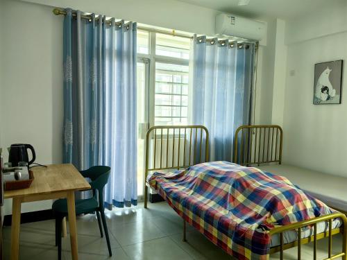 a bedroom with a bed and a table and a window at Cozy home of Orchid in Haikou
