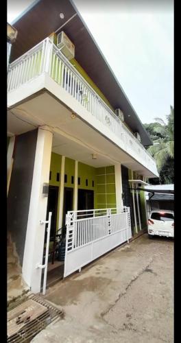 a house with a white railing and a balcony at Homestay Rafatar in Rantaupanjang