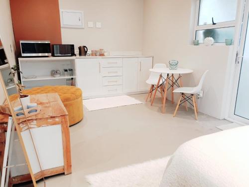 a white kitchen with a table and a chair at Sea Breeze Cottage in Cape Town