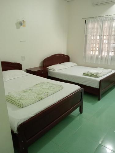 a room with two beds and a window at Homestay Nhật Thi in Mui Ne