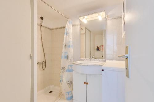 La salle de bains blanche est pourvue d'un lavabo et d'une douche. dans l'établissement Escale et instants de détente à St-Vincent-sur-Jard, à Saint-Vincent-sur-Jard