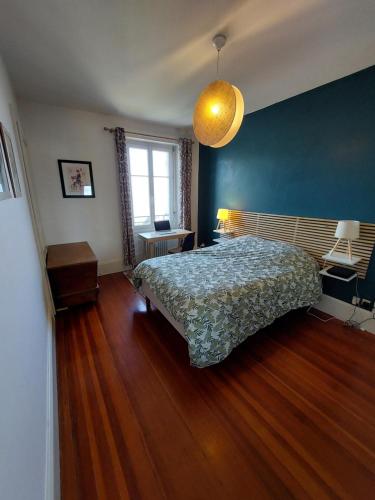 um quarto com uma cama e uma parede azul em Le Mirabeau Vue Lac em Évian-les-Bains