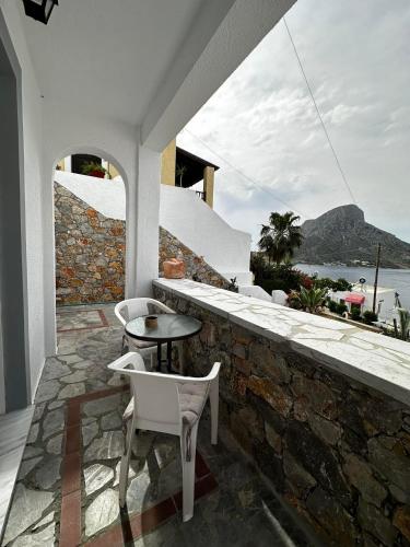a patio with a table and chairs on a stone wall at Elenis Studios&Apartments in Masouri