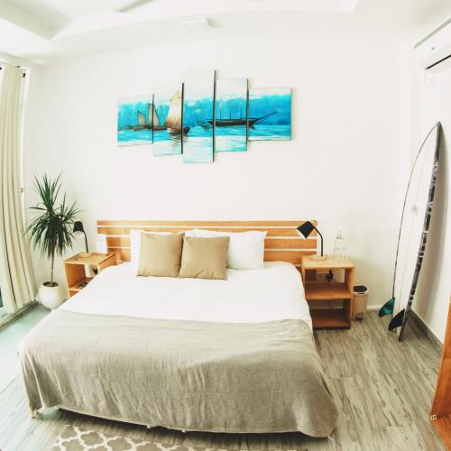 a bedroom with a bed and a painting on the wall at TWIN PALMS 'Surfhouse' in Thulusdhoo