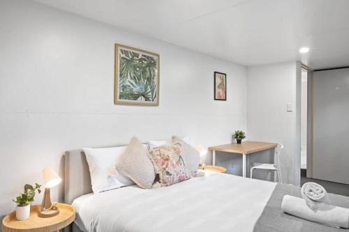 Dormitorio blanco con cama y mesa en Pymble private room Sleeps 2 en Pymble