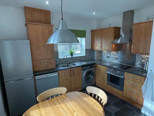 Seaham Sea View 2 bedroom apartment في سيهام: مطبخ مع طاولة ومغسلة وغسالة صحون