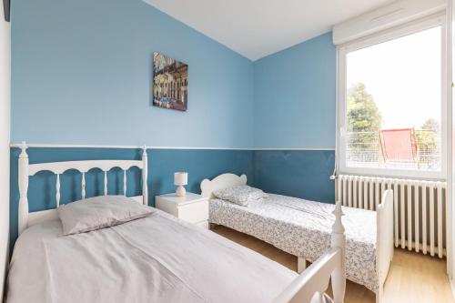 a blue bedroom with two beds and a window at La Maison Coquelicot - Havre de paix à Rennes in Rennes