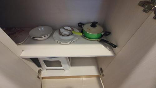 a small white shelf with pots and pans on it at Vanilla One Residence Apartment Batam in Batam Center