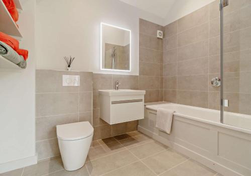 a bathroom with a toilet and a tub and a sink at The Domini Cowshed at Village Farm in Market Weston