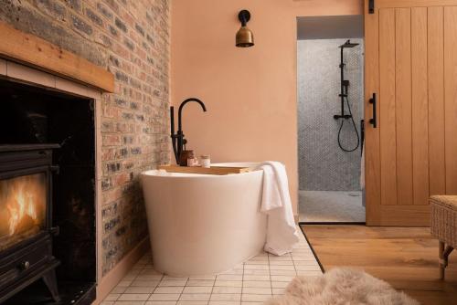 a bath tub in a bathroom with a fireplace at East Lodge, Home Farm in Belford
