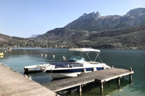 a boat is docked at a dock on a lake at Balcon sur le lac charmant T3 avec vue spectaculaire in Duingt