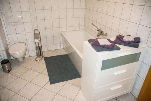 a white bathroom with a tub and a toilet at Schöne 2-Raum-Wohnung im Zentrum Waltershausens in Waltershausen