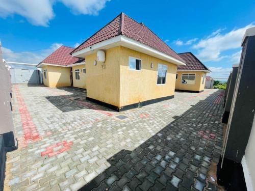 une maison jaune avec un toit rouge dans une allée dans l'établissement Shooting star Lodge, à Dodoma