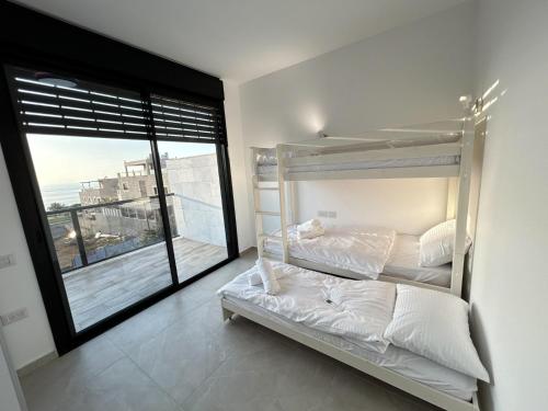1 Schlafzimmer mit 2 Etagenbetten und einem großen Fenster in der Unterkunft נוף נתניה in Netanya