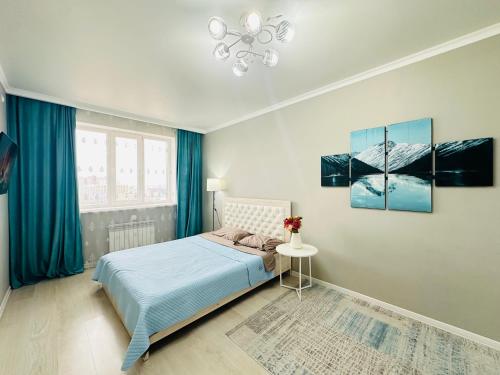 a bedroom with a bed with blue curtains and a window at Роза Багланова in Astana