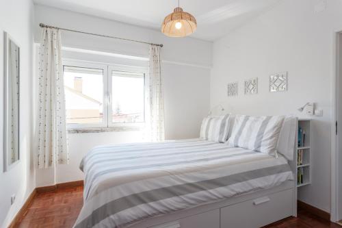 a white bedroom with a bed and a window at Beach House Cascais in Estoril