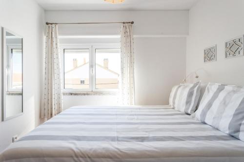 a white bedroom with a bed and two windows at Beach House Cascais Close to Lisbon & Sintra in Estoril