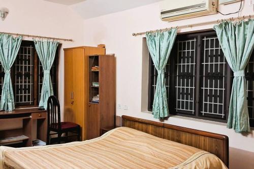 a bedroom with a bed and a desk and windows at Unwind @ Serene Retreat in Palakkad