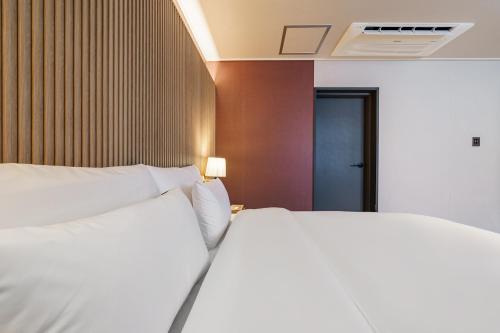 a hotel room with a bed with white pillows at Browndot Samcheonpo in Sacheon