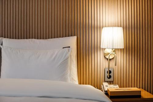 a bed with a white pillow and a lamp on a table at Browndot Samcheonpo in Sacheon