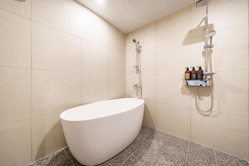 a bathroom with a white tub and a shower at Browndot Samcheonpo in Sacheon