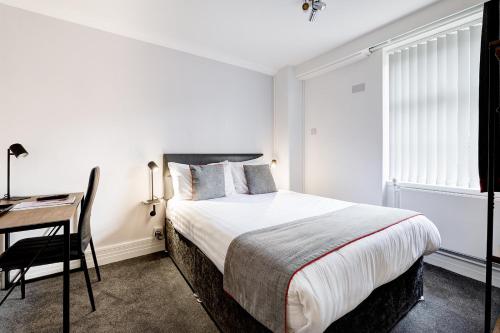 a bedroom with a bed and a desk and a desk at The Derby Conference Centre and Hotel in Derby