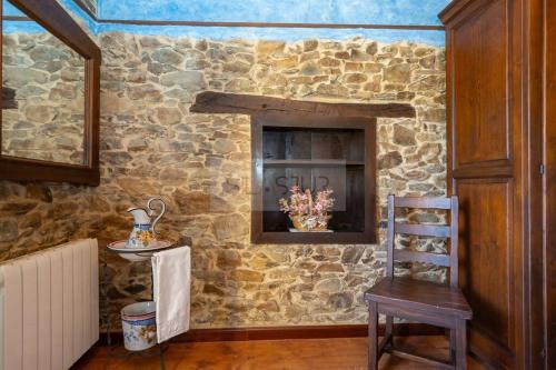 a room with a stone wall with a chair and a fireplace at La Casona Del Cura III in Pravia
