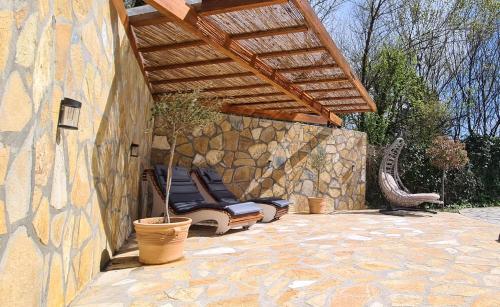 une terrasse avec un mur en pierre et une pergola en bois. dans l'établissement Villa Stefania, à Ágios Ioánnis