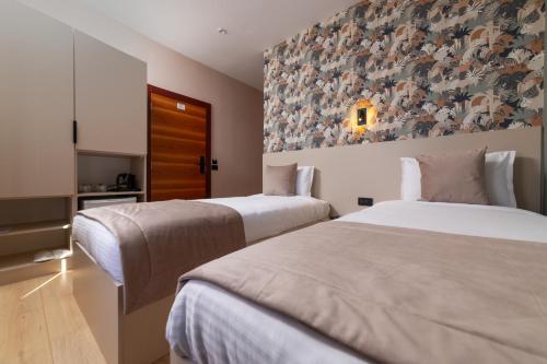 two beds in a hotel room with a painting on the wall at Hotel Ma Belle in Pristina