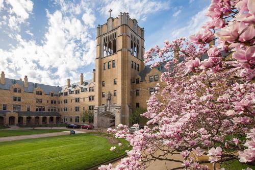 a building with a clock tower with pink flowers at The Lucky Charm Home of the Fighting Irish! BBQ Outdoor Games Coffee in South Bend