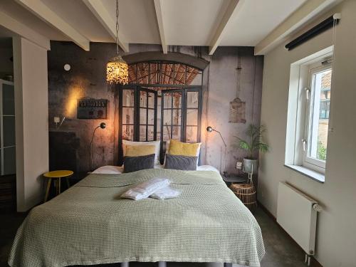 a bedroom with a large bed and a chandelier at Dit Eiland (2p) in Hollum