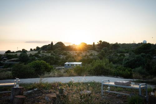 un banco en un campo con la puesta de sol en el fondo en Natura Escape in Val di Noto, en Noto