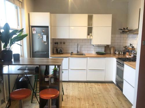 a kitchen with white cabinets and a table and a refrigerator at 2 Bed Apt with air con - 10min to Canonbury Station in London