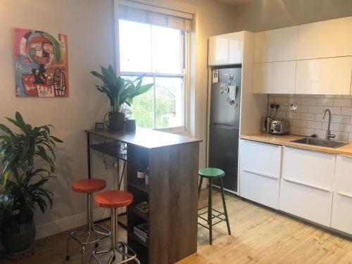 a kitchen with a counter and stools in it at 2 Bed Apt with air con - 10min to Canonbury Station in London