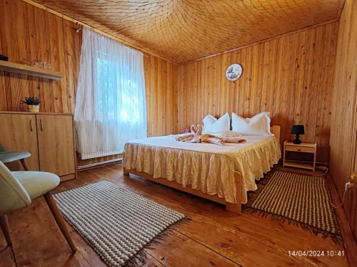 a bedroom with a bed with wooden walls and a window at Casa Soveja Rucareni in Soveja