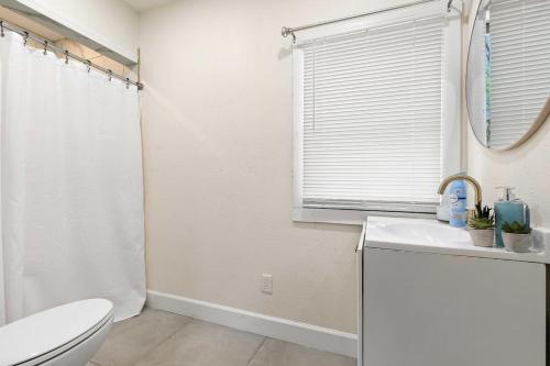 ein Bad mit einem WC, einem Waschbecken und einem Fenster in der Unterkunft The Lily Pad Modern Cottage In The City in Mobile