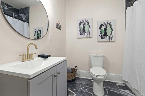 ein Badezimmer mit einem Waschbecken, einem WC und einem Spiegel in der Unterkunft Modern Escape in Historic District in Mobile