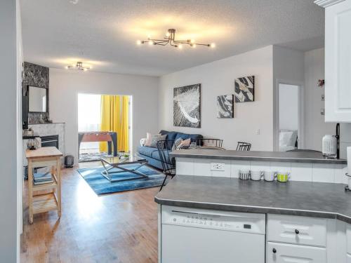 een keuken en een woonkamer met een bank en een tafel bij Fun and Colourful Condo w Foosball Parking Coffee in Calgary