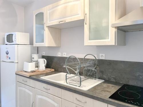une cuisine avec des armoires blanches et un évier dans l'établissement Spacieux appartement sur les quais de la Chaume - 6 pers, à Les Sables-dʼOlonne